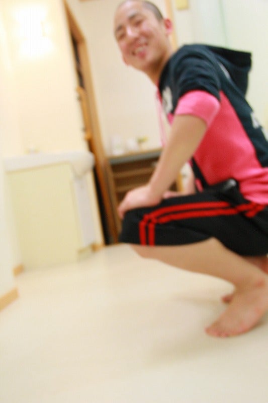 笑顔でしゃがむ男性、剣道部員